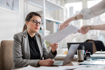 Manager giving feedback to young employee on her draft document. Ambitious young woman working in a...