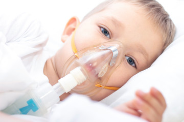 boy with an inhaler mask - respiratory problems in asthma. a boy with an inhaler mask lies in bed...
