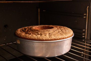 Delicious lemon cake coming out of the oven, round shape, dark background