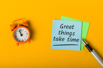 Great things take time - written in note on desk with little clock