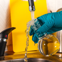 water purification specialist tap water pours into a glass flask.