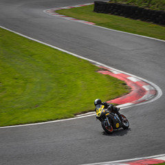 A panning shot of a black and yellow racing bike speeding round corners on a racetrack.
