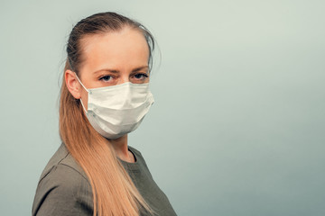 A girl is putting on a protective mask. Respiratory protection from coronavirus. Personal protective equipment for a pandemic of a viral infection. Covid-19.