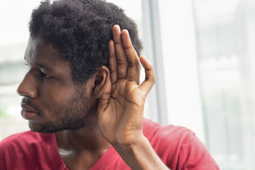 sad frustrated unhappy African black man listening ear to bad news or having hearing impair, hard...