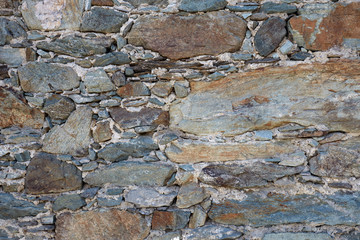 The texture of the wall of stone. Wall of gray, brown, orange, brown stone and concrete.