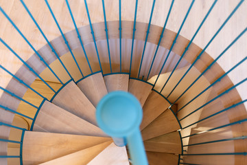 Spiral staircase, forged blue handrail and wooden steps in modern home. The view from the top.