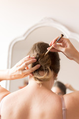 Naklejka premium Young woman portrait putting on make up in front of a mirror