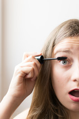 Young woman portrait putting on black mascara
