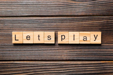 lets play word written on wood block. lets play text on wooden table for your desing, concept
