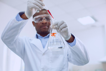 Serious intelligent male scientist wearing protective glasses