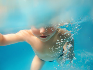 Fototapeta na wymiar Young caucasian boy underwater in the swimming pool