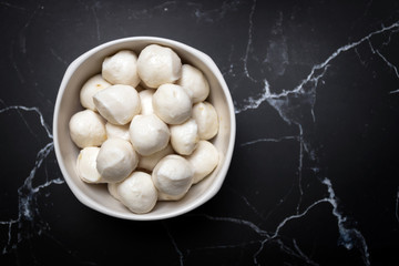 Boiled fish balls in white bowl on black mable table with copy space; top view