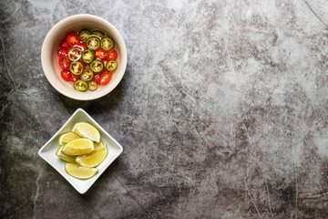 Green and red pickled chili in vinegar with lime; sour taste. Top view with copy space on background. 