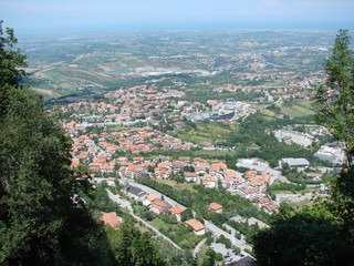 Fototapeta premium Top view of a small Central European country under a summer midday blue sky against the backdrop of the Adriatic in a foggy horizon.