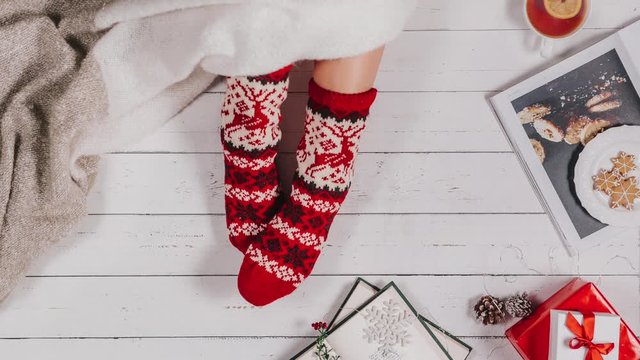 stop motion animation, the sock is worn on the leg, the plaid covers the legs, a mug of tea appears, a female hand takes the cup