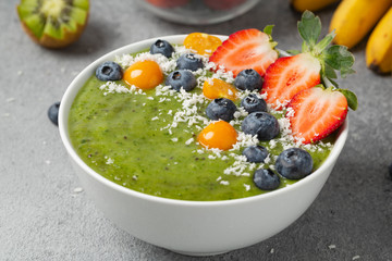 Healthy Breakfast green smoothie bowl with banana, kiwi, strawberry, blueberry and spinach.