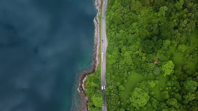 Cars and lorry driving along ocean road in Scotland, summer aerial birds eye view