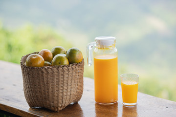 Glasses of fresh tangerine juice and fruits on wooden table