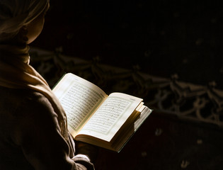 Muslim woman under the sunlight reading Quran