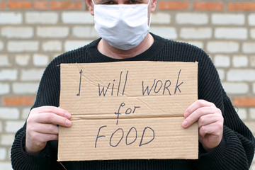 concept unemployment and coronavirus a man in a medical hygienic mask is holding a cardboard tablet...