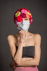 Woman with medical mask wearing artificial flower hat isolated over grey background. copy space