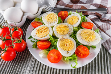 salad with boiled chicken eggs and cherry tomatoes on a wooden rustic background