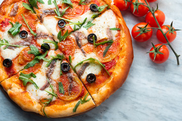 Pizza fatta in casa con rucola, olive, mozzarella, pomodoro e olive nere 