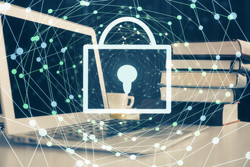 Double exposure of desktop with computer and lock icon hologram. Concept of data safety.