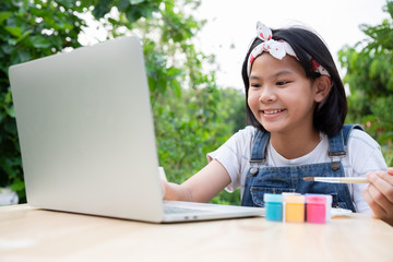 Two little girls are learning through online lessons in the front garden. They were smile and happiness to learn art subject. Protect corona virus new strain, or COVID-19. Education from home.