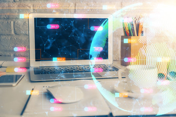 Double exposure of desktop with computer and world map hologram. International data network concept.