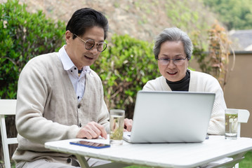 Fototapeta na wymiar An Asian elderly couple is using a laptop