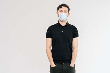 Portrait of serious young man wearing medical mask, looking at camera, isolated on white background. Prevention of virus infection. Concept of Coronavirus COVID-19 Pandemic.