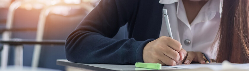 Exam at school with student's taking educational admission test in class, thinking hard, writing answer in university classroom, education and world literacy day concept