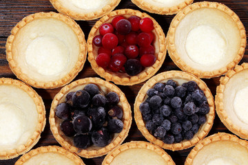 Tasty tartlets with different berries,cranberries,bilberry,blackcurrant . Berry tartlets. Cake with berries. Dessert with berries. Wooden background. Healthy food, vitamins.