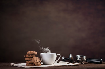 Coffee, cookies and utensils for coffee maker on dark brown background with copy space for text
