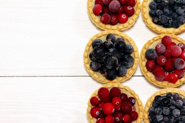 Tasty tartlets with different berries,cranberries,bilberry,blackcurrant . Berry tartlets. Cake with berries. Dessert with berries. Wooden background. Copy space. Healthy food, vitamins.