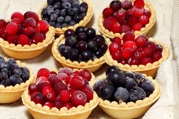 Tasty tartlets with different berries,cranberries,bilberry,blackcurrant . Berry tartlets. Cake with berries. Dessert with berries. Wooden background. Healthy food, vitamins.