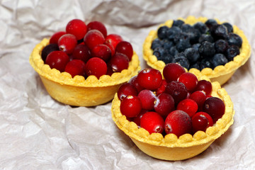 Tasty tartlets with different berries,cranberries,bilberry,blackcurrant . Berry tartlets. Cake with berries. Dessert with berries. Wooden background. Healthy food, vitamins.