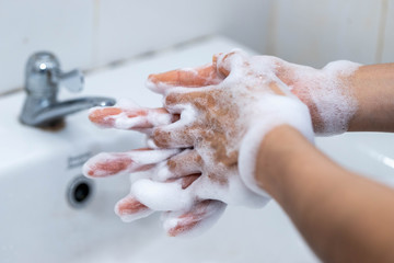 Fototapeta premium Close up woman use soap and washing hands under the water tap in the bathroom for coronavirus and bacteria germs spreading protection,