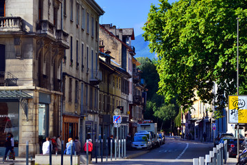 Chambéry, France - August 11th 2017 : View of a busy street with beautiful old buildings. At the end of the road, you can see mountains.