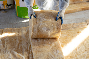 Foreman in overalls working with rockwool insulation material