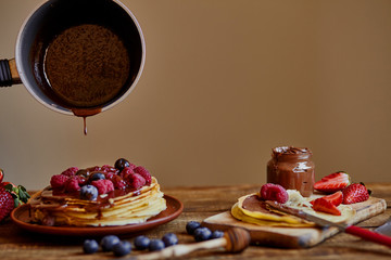 Homemade crepes, tasty thin pancakes with chocolate and fruits on the rustic table