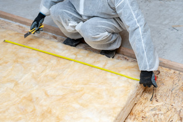 Workman in overalls working with rockwool insulation material