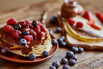 Homemade crepes, tasty thin pancakes with chocolate and fruits on the rustic table