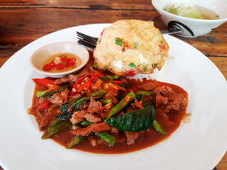 Beef stir-fried with red curry paste served with steamed rice and omelet