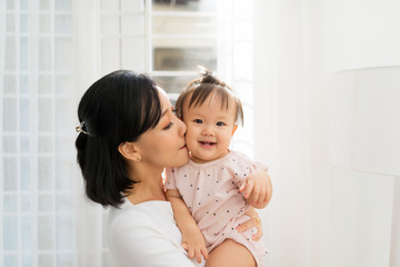 Portrait of happy vietnamese mother hugging with her cute little daughter at home