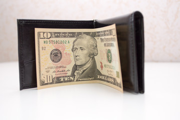 empty leather wallet with only 10 dollar as a symbol of modern poor person poverty and economic...