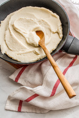 Cauliflower bechamel sauce on a pan on top of a wooden board. Side view. 