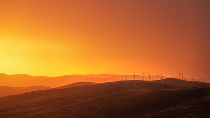 Naklejka na ściany i meble Windmills in an incredible orange sunset panorama. 