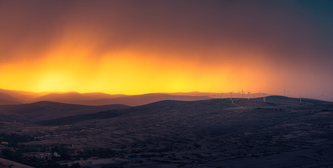 Panorama of windmills  at the the top of a mountain in a stunning sunset